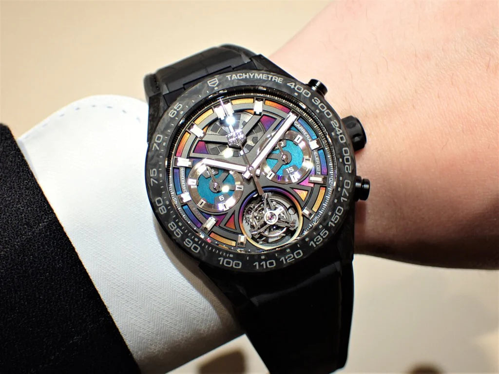 Luxury watch with a black strap and colorful face on a wrist.